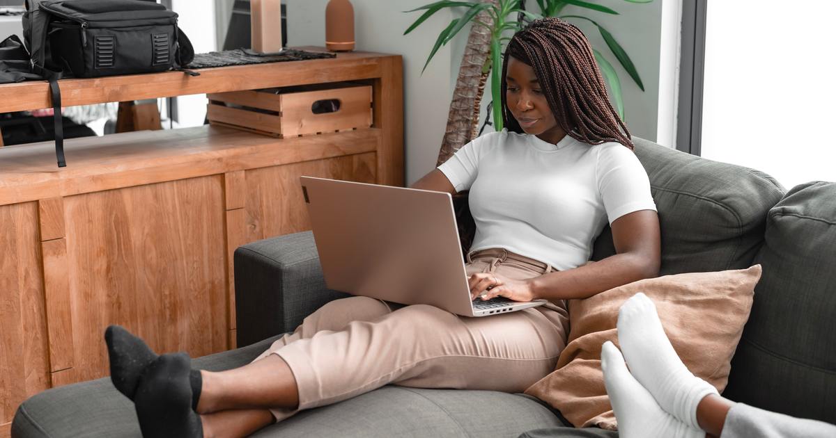 Woman sitting on couch typing on laptop